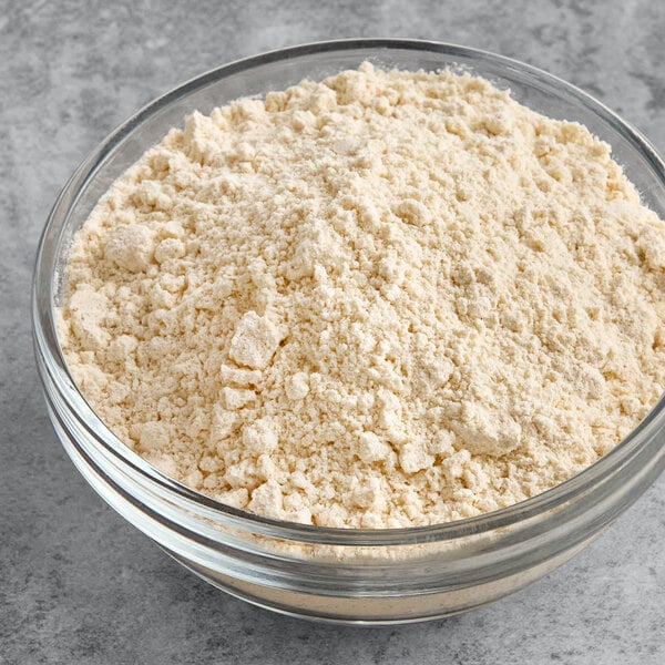 A clear glass bowl filled with light beige funnel cake mix powder.
