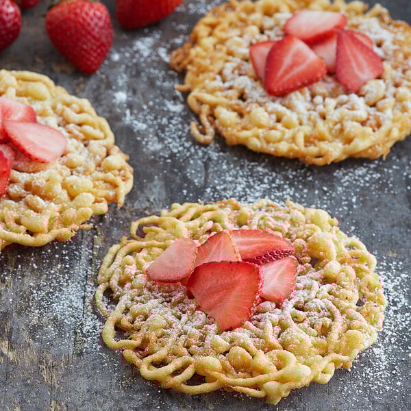 A plate of funnel cakes topped with powdered sugar and sliced strawberries.
