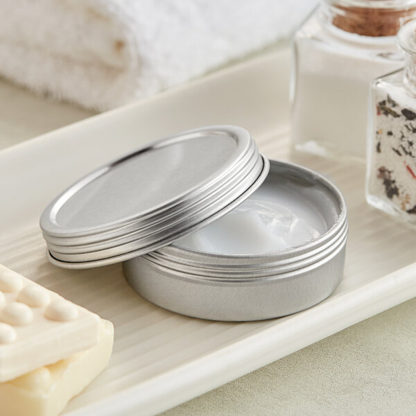 A silver tin with a screw top filled with a white substance.