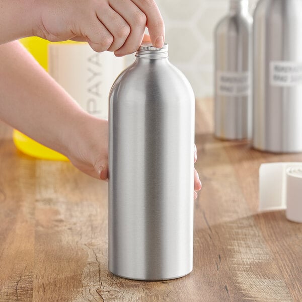 A person holding a silver aluminum bottle with a lid.