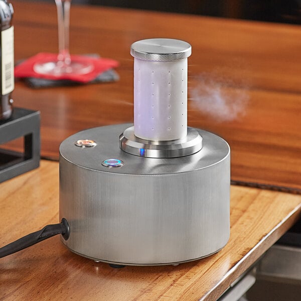 An Avantco countertop dry ice machine on a wooden table with a glass.
