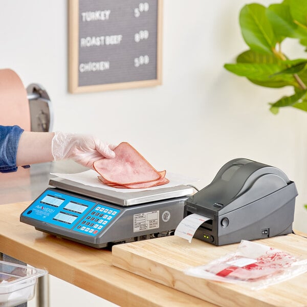 A person weighing meat on an AvaWeigh digital price computing scale.