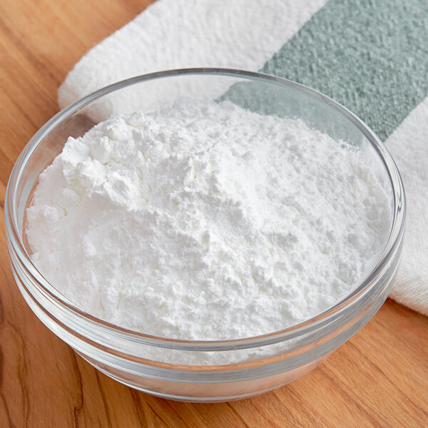 A bowl of Clabber Girl baking powder on a wooden table.