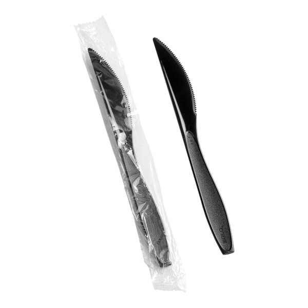 A heavy weight black plastic knife, with one shown individually wrapped in plastic packaging.