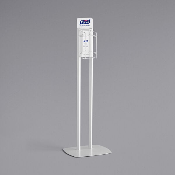 A white rectangular Purell dispenser stand with a metal frame holding a sign.