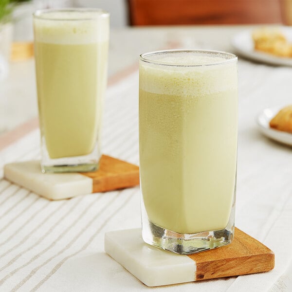 Two glasses of DaVinci Gourmet matcha green tea on a brown table with white trim.
