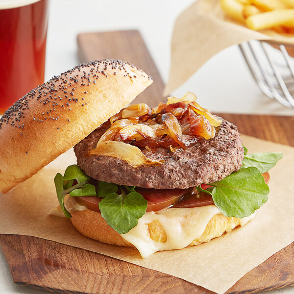 A TenderBison burger with onions and lettuce on a wooden board.