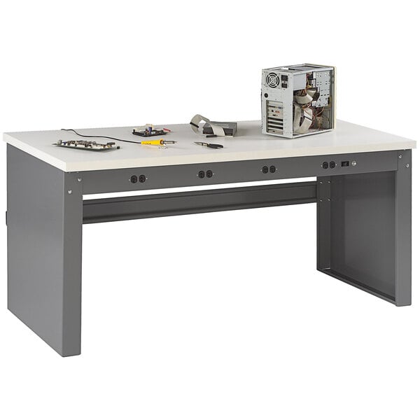 A white Tennsco workbench with a rectangular plastic laminate top and panel legs with electrical equipment on it.