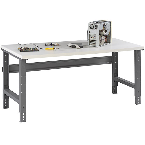 A white Tennsco plastic laminate top workbench with adjustable legs.