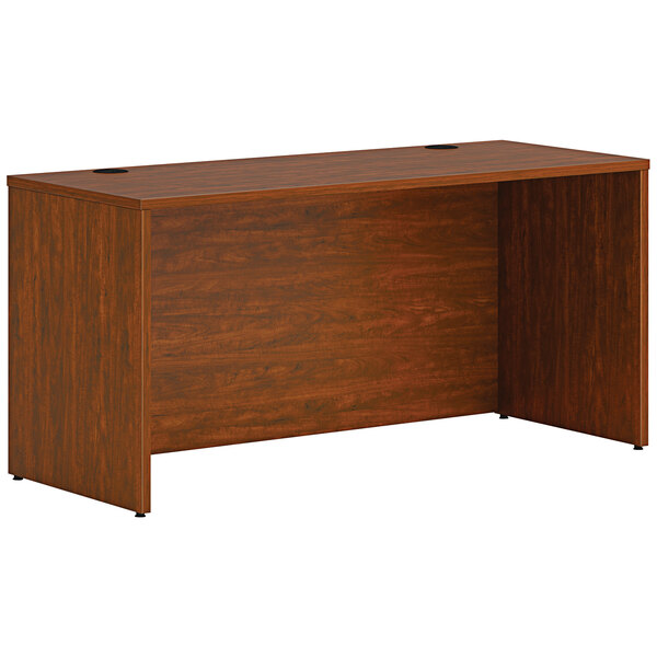 A HON russet cherry laminate credenza shell on a wooden desk.