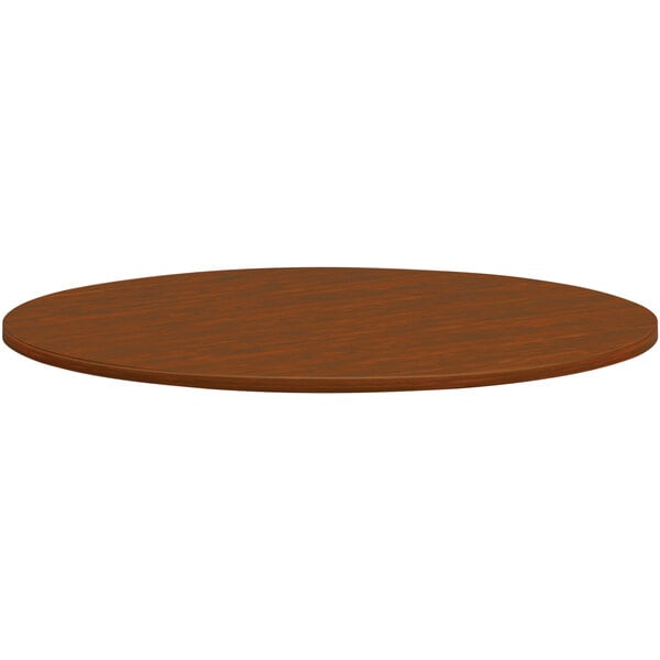 A brown circular HON conference table top with a wood surface.