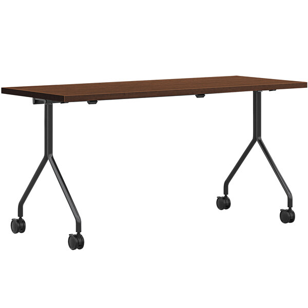A HON Shaker Cherry laminate rectangular table with wheels.
