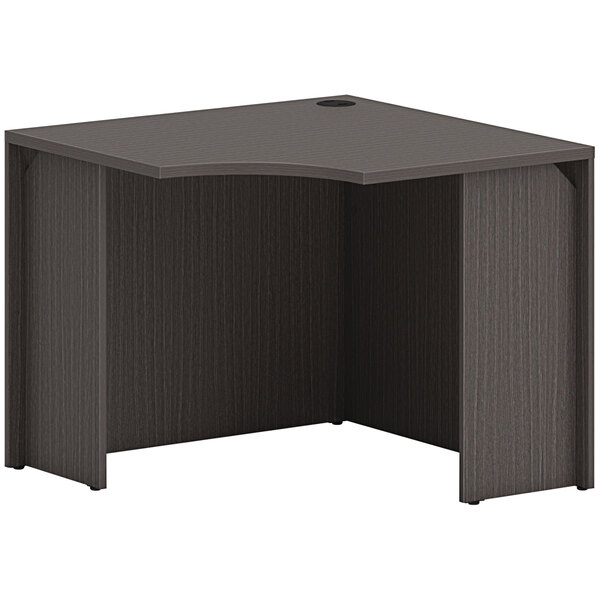 A black corner desk with a curved front and a hole in the top.