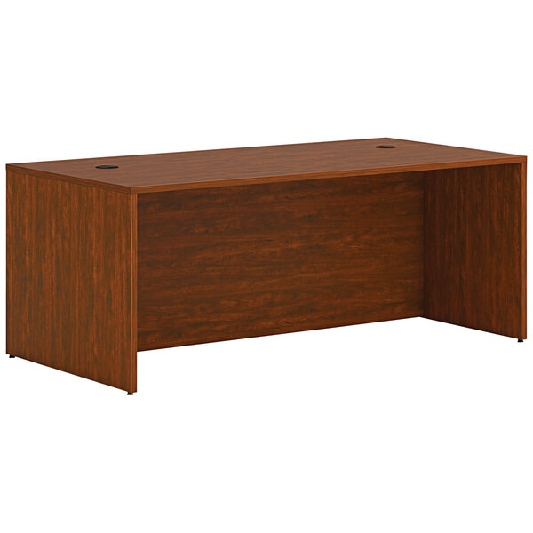 A HON russet cherry laminate desk shell on a wooden desk.