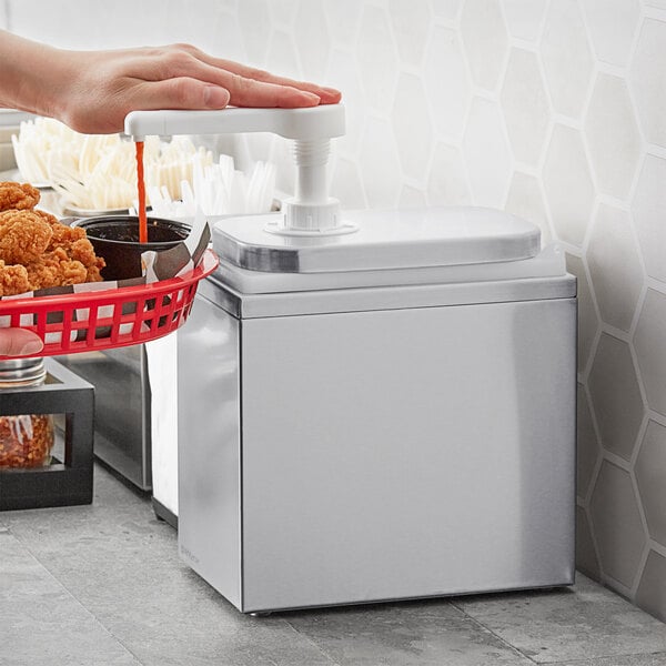 A hand using a ServSense stainless steel condiment pump to pour sauce into a basket.