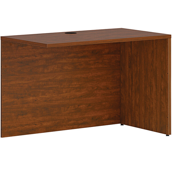 A HON russet cherry desk return shell with a wooden top and a hole.