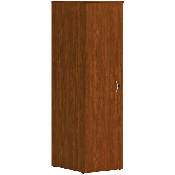 A HON russet cherry laminate wardrobe cabinet with a wooden door and silver handle.