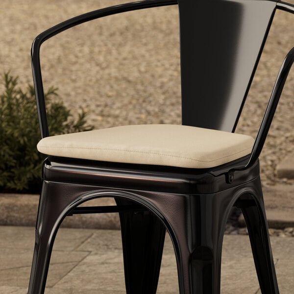 A black Lancaster Table & Seating chair with a tan fabric cushion on top.