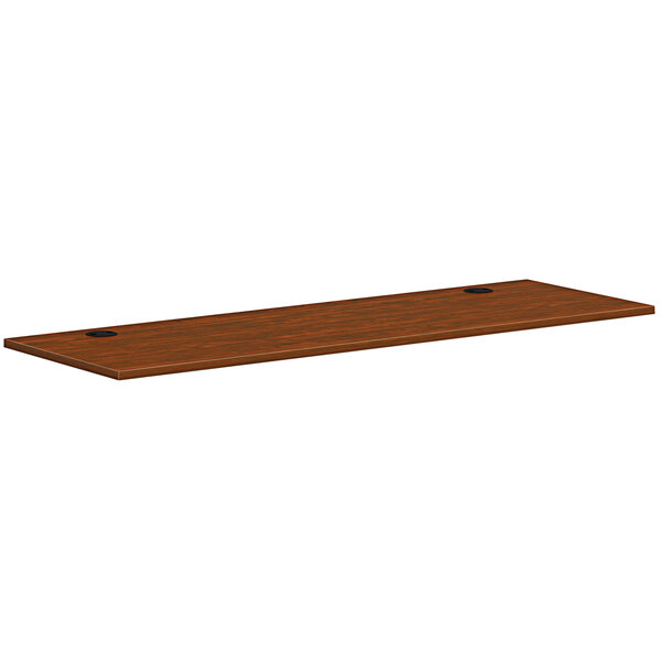 A rectangular wooden HON worksurface in russet cherry with two black holes.