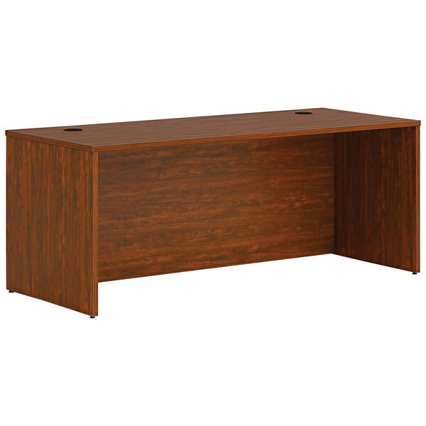 A HON russet cherry laminate desk shell on a wooden table.