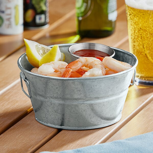 A close up of an American Metalcraft galvanized metal tub with a bowl of shrimp and lemons.