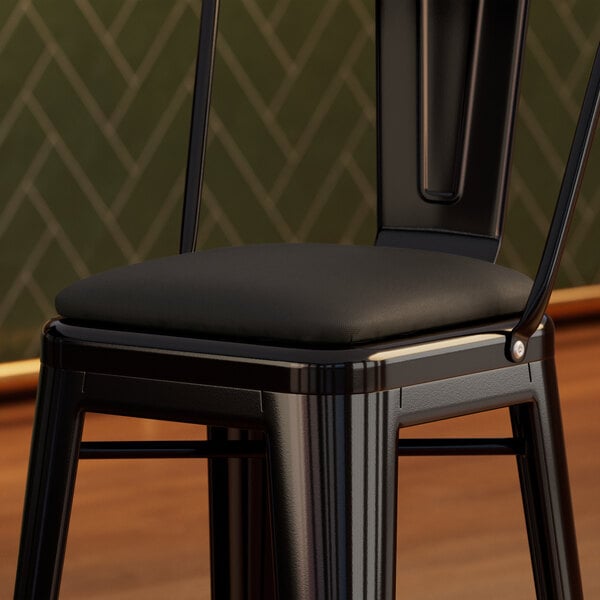 A black vinyl cushion on a Lancaster Table & Seating Alloy Barstool.