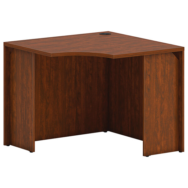 A HON russet cherry laminate corner desk shell with a wooden top and a hole.