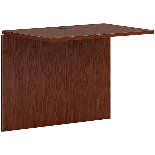 A rectangular brown HON office bridge on a wooden desk.