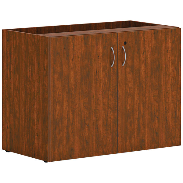 A russet cherry wooden cabinet with two doors and two drawers with silver handles.