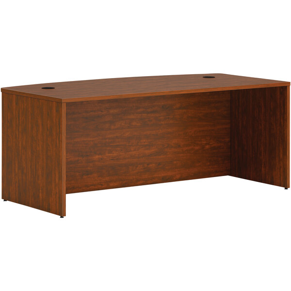A HON russet cherry wooden desk with a bow front and two holes.