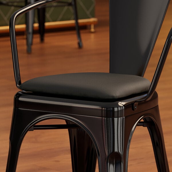 A Lancaster Table & Seating black vinyl cushion on a black metal chair.