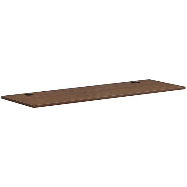 A brown rectangular HON worksurface with two holes.