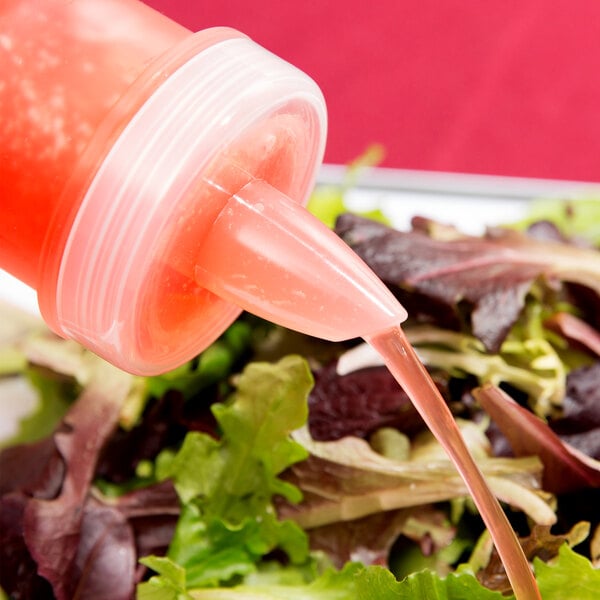 A GET Juice Pour Lid pouring liquid from a bottle onto a salad.