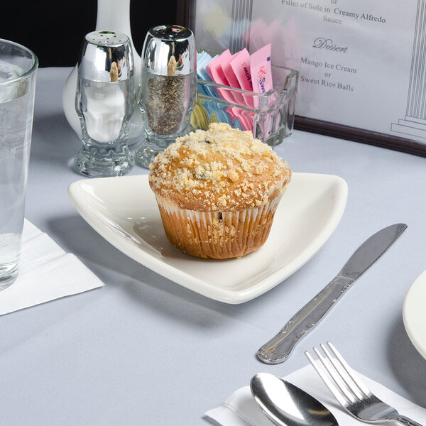 A Tuxton eggshell triangle china plate with a muffin on it.