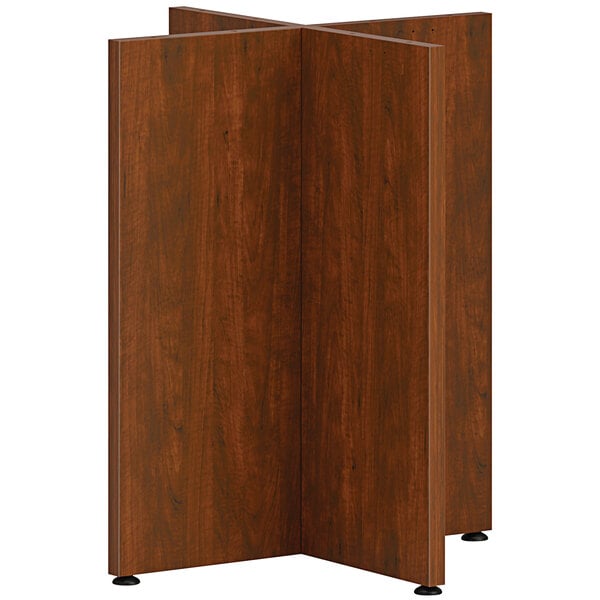 A HON russet cherry wood X-base for a table with wood paneling.
