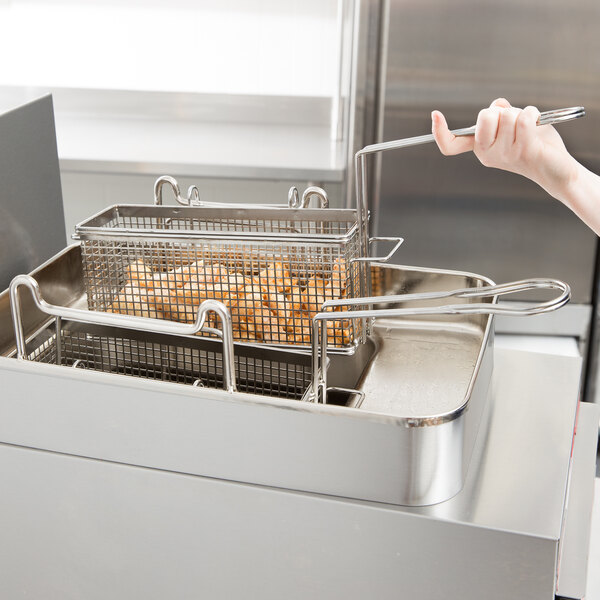 A person holding a Star twin fryer basket with food in it.