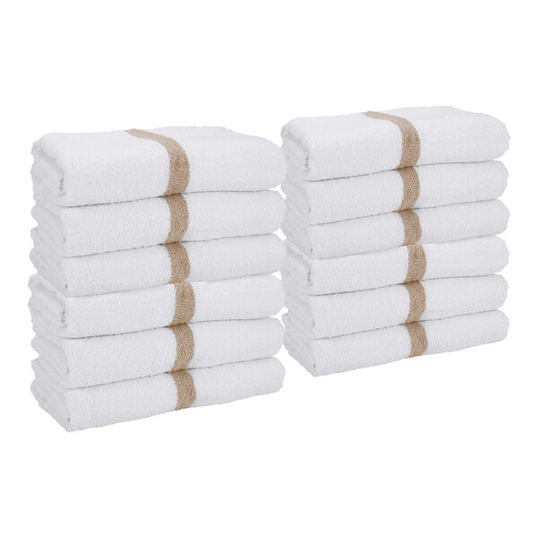 Two stacks of white towels with a beige stripe, each stack containing six neatly folded towels.