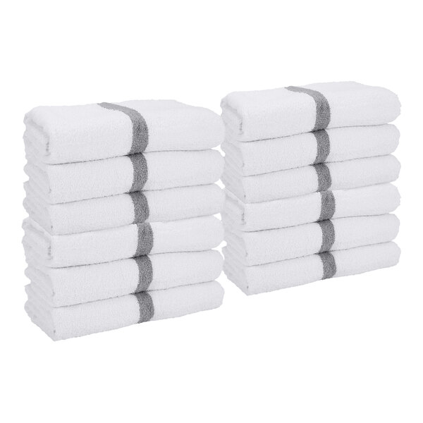 Two stacks of white towels, each with a gray stripe near one end, neatly folded and arranged side by side.