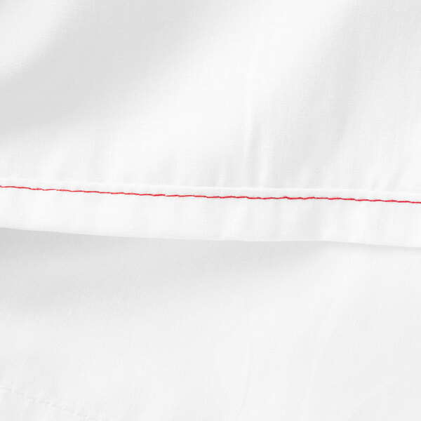 A close up of a white Monarch Brands cotton/polyester flat sheet.