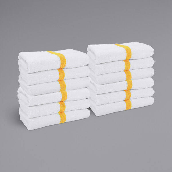 A stack of white towels with yellow center stripes.