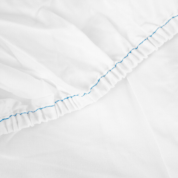A white Monarch Brands fitted sheet with blue stitching.