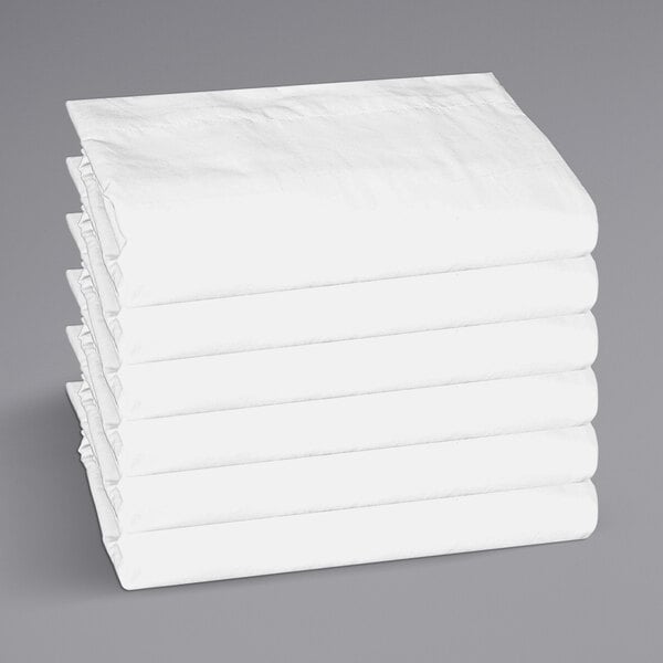 A stack of white folded Monarch Brands hotel sheets.