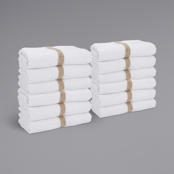 A stack of white towels with beige center stripes.