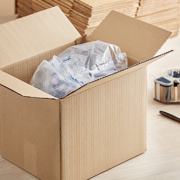 A Lavex kraft cardboard shipping box on a table filled with paper and pens.