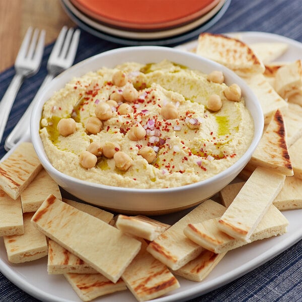 A bowl of Grecian Delight Traditional hummus with chickpeas and spices and a plate of crackers.