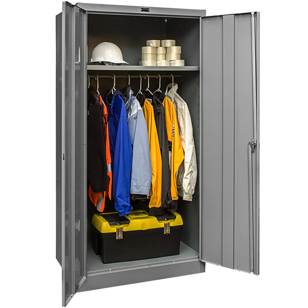 A gray metal Hallowell wardrobe cabinet with solid doors filled with clothes and tools.