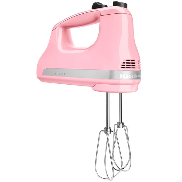 A KitchenAid Guava Glaze 5-speed hand mixer with whisks.