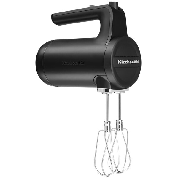 A matte black KitchenAid cordless hand mixer with a handle and wire whisk attachment.