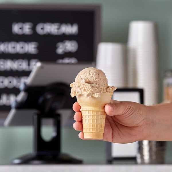 A hand holding a JOY flat bottom cake cone filled with ice cream.