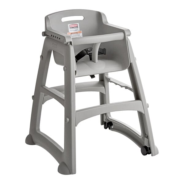 A gray plastic restaurant high chair with wheels and a safety harness.